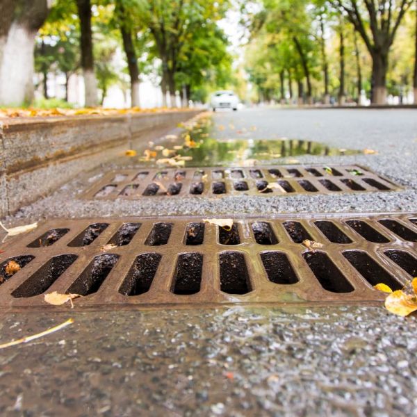 Strasse mit Kanalabfluss im Vordergrund