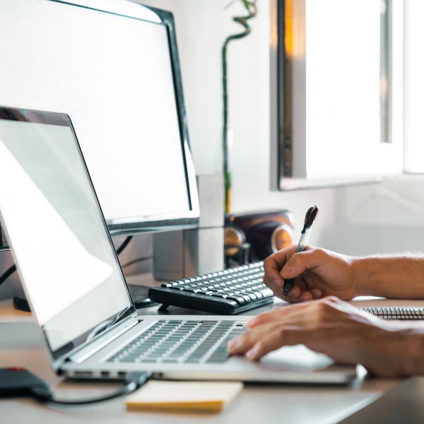 Hände einer Person an Bildschirm und Laptop