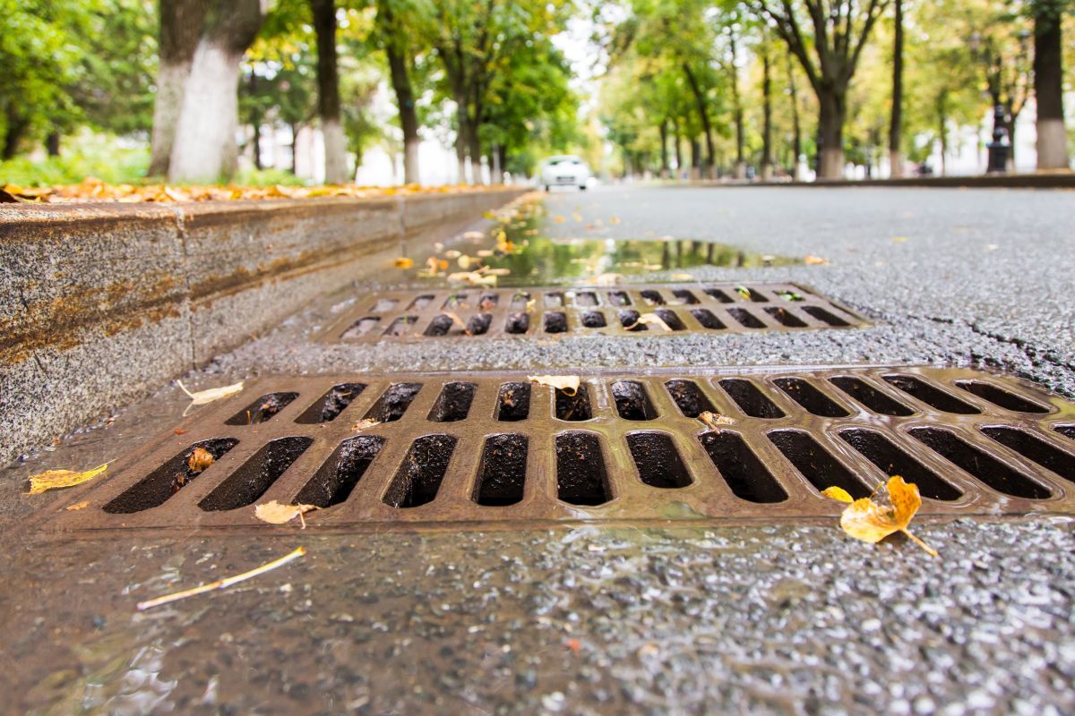 Strasse mit Kanalabfluss im Vordergrund