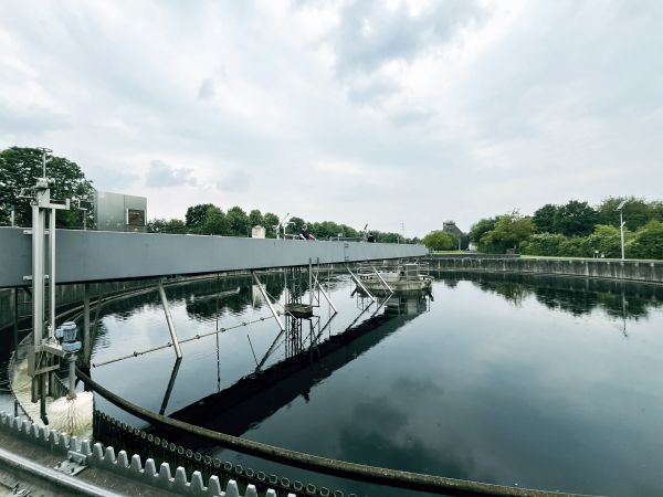 Klärbecken mit Räumer und Himmelspiegelung im Wasser